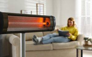 infrared heating in use while woman reads book on sofa in the background